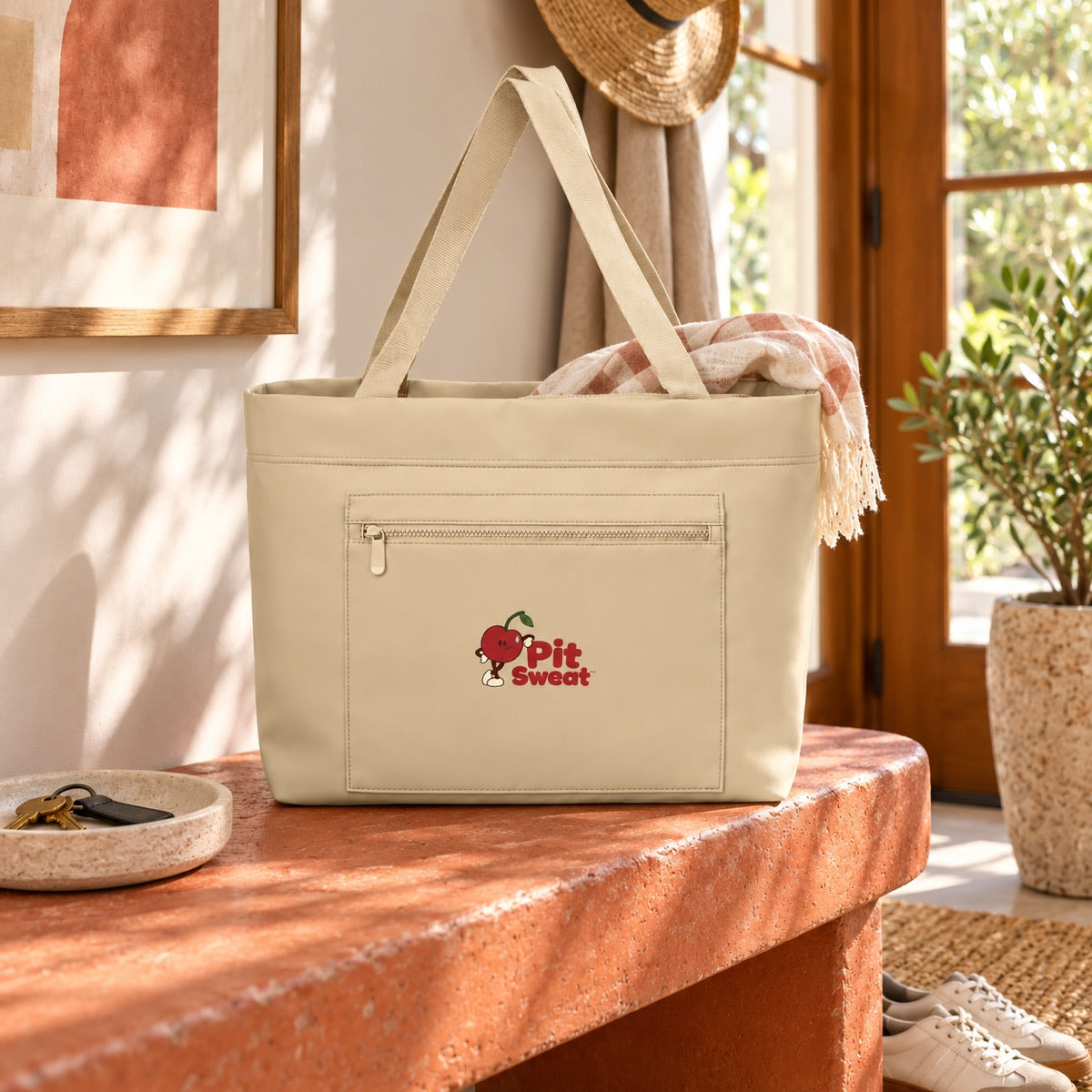 Sahara matte carryall with leaning Pit on its front pocket, beside a sunny doorway