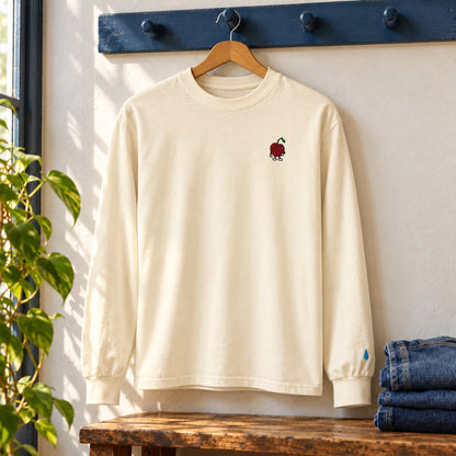 Ecru long-sleeve tee on a blue peg rail, with chest Pit and a small wrist droplet