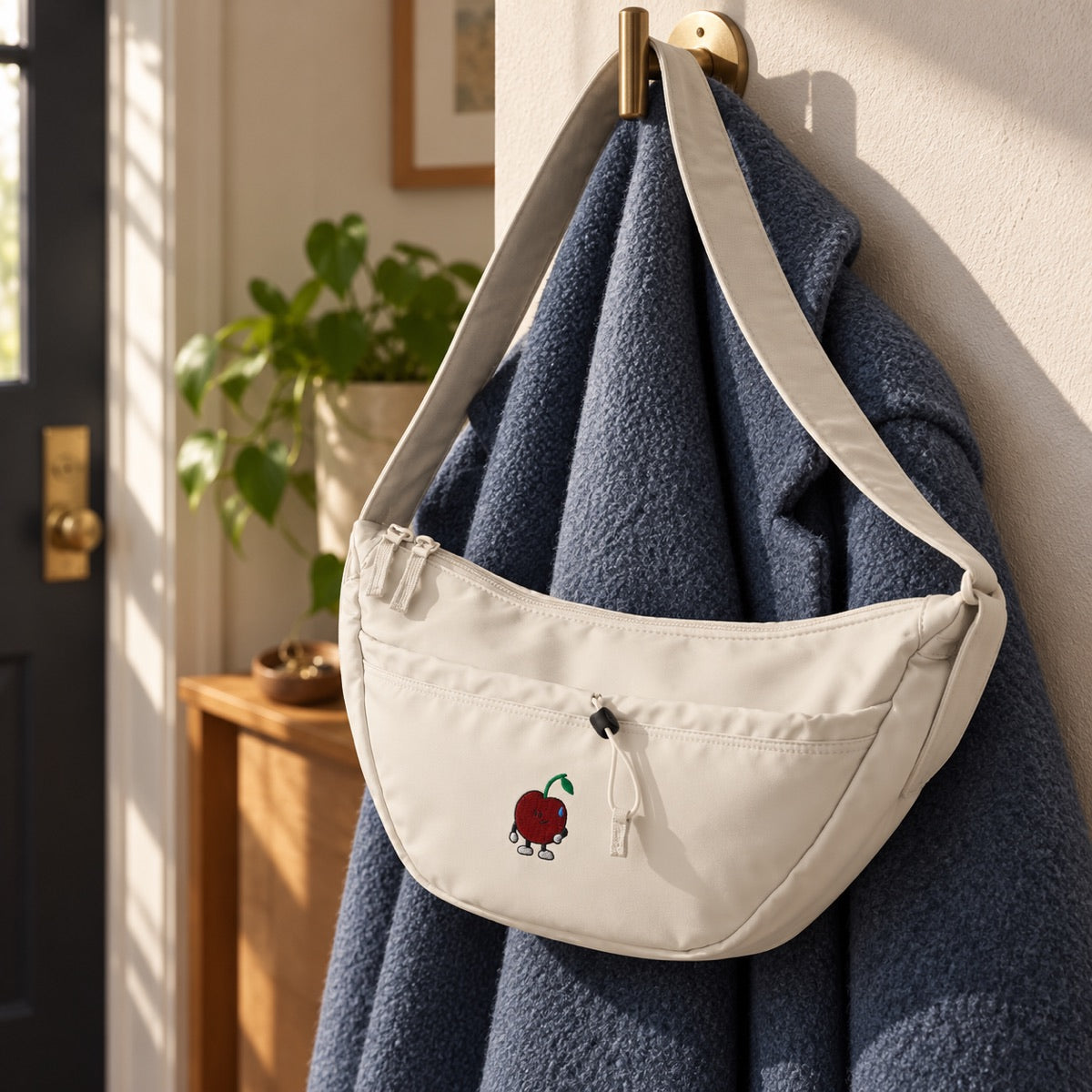 Natural Stone Little Pit crossbody hanging over a blue coat in an entryway