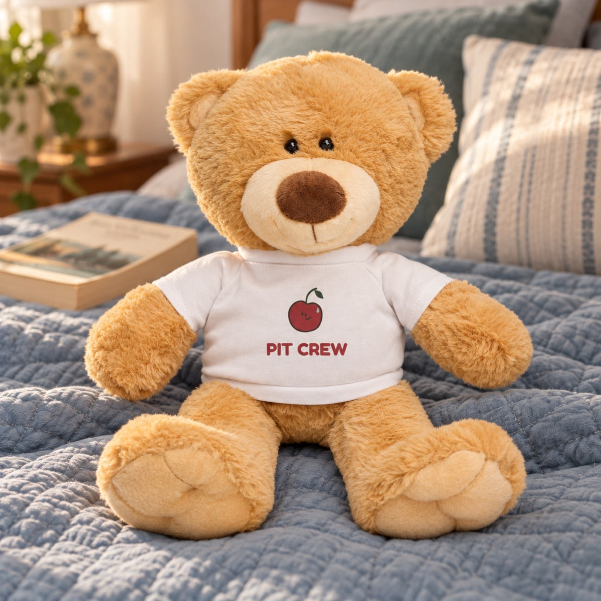 Golden Pit Crew teddy sitting on a blue quilt in a sunlit bedroom