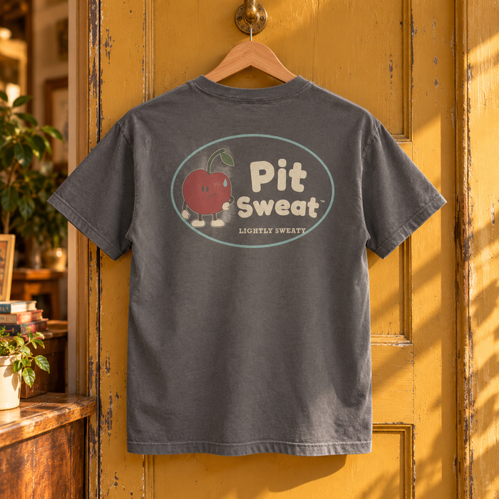 Old Shop Youth Tee — Pepper — large back graphic on a wooden hanger in a warm vintage shop