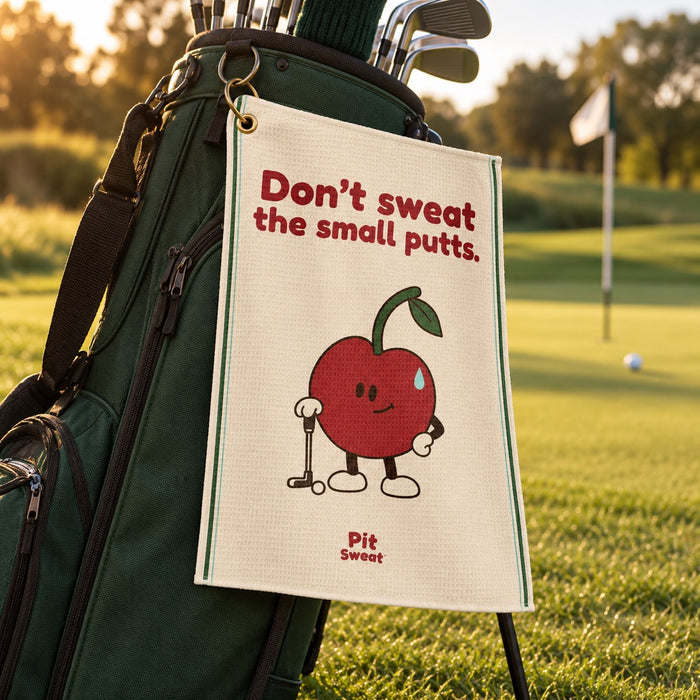 Don’t sweat the small putts golf towel clipped to a green golf bag beside the course
