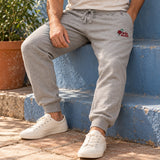 Carbon Grey joggers with leaning Pit and the rounded wordmark, worn on a blue courtyard step